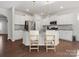 An open-concept kitchen features an island with bar stools, stainless steel appliances, and sleek white cabinetry at 3036 Whipcord Dr, Waxhaw, NC 28173