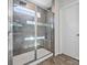 Bathroom featuring a shower with glass doors, gray tile, a bench, and a window for natural light at 3036 Whipcord Dr, Waxhaw, NC 28173