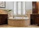Bright bathroom highlighting a textured round soaking tub, travertine tile backsplash and dark cabinets at 325 Ivy Arbor Cir, Rock Hill, SC 29732