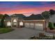 Stately brick home with a grand entrance, a three-car garage, and professional landscaping at sunset at 3988 Channel Point Ln, Denver, NC 28037