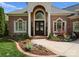 Stately brick home with arched entryway, decorative glass doors, and lush, colorful landscaping at 3988 Channel Point Ln, Denver, NC 28037