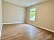 An empty bedroom featuring wood-look floors, neutral walls, and a bright window at 4418 Palustris Ct, Charlotte, NC 28269