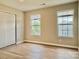 Bright bedroom with wood-look flooring, two windows, and a sliding door closet at 4418 Palustris Ct, Charlotte, NC 28269