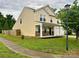 Side view of a two-story home showcasing the landscaped yard and a charming front porch with stone accents at 4418 Palustris Ct, Charlotte, NC 28269