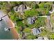 Expansive aerial view of a luxurious lakeside property with lush landscaping, a private dock, and sandy beach at 4628 Sierra View Dr, Denver, NC 28037