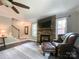 Comfortable living room featuring a stone fireplace, hardwood floors, a ceiling fan, and neutral colored walls at 4823 Antioch Church Rd, Weddington, NC 28104