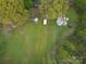 Aerial view of landscaped property featuring mature trees, grass, and outdoor structures at 5319 Springdale Ave, Mint Hill, NC 28227