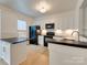 Well-lit kitchen with modern appliances, white cabinets, black countertops, and a kitchen island at 5430 Dockery Dr, Charlotte, NC 28209