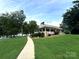 View of a waterfront property with a beautiful lawn, and a covered porch with white railing at 676 Chapel Hill Dr, Troy, NC 27371