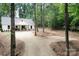 Exterior shot of the home nestled among mature trees and a long gravel driveway at 676 Chapel Hill Dr, Troy, NC 27371