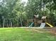 Outdoor playground area featuring swings, a climbing wall, and slides, surrounded by lush greenery at 676 Chapel Hill Dr, Troy, NC 27371