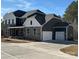 Beautiful two-story home featuring a three-car garage, stone accents, dark siding, and white trim under a brilliant blue sky at 7001 New Town Rd, Waxhaw, NC 28173