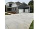 View of the home's side with a spacious concrete driveway, a two-car garage, and stone and gray siding at 7001 New Town Rd, Waxhaw, NC 28173