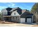 Beautiful two-story home featuring stone accents, a covered porch, attached three-car garage, and a manicured lawn at 7001 New Town Rd, Waxhaw, NC 28173