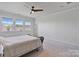 Bright bedroom features plush carpet, a modern ceiling fan, and ample natural light from three windows at 7957 Reunion Row Dr, Charlotte, NC 28277