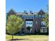 Charming brick townhome featuring dormer windows, a well-manicured lawn, and verdant landscaping at 7957 Reunion Row Dr, Charlotte, NC 28277