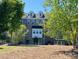 Brick townhome surrounded by mature landscaping and lush greenery on a bright, sunny day at 7957 Reunion Row Dr, Charlotte, NC 28277