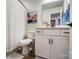Bright bathroom features a single sink vanity, a shower and a striped shower curtain at 1112 Drummond Ave, Charlotte, NC 28205