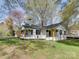 Charming exterior view of a white home featuring a black roof, front porch and landscaped yard at 1209 Mount Ulla Hwy, Mooresville, NC 28115