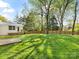 Expansive, grassy backyard features a wooden fence, mature trees, and a sandbox for outdoor enjoyment at 1210 Sewickley Dr, Charlotte, NC 28209