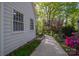 The exterior side of a home that has a stone walkway that leads to a lush backyard and mature trees at 1220 Oakwood Ave, Gastonia, NC 28052