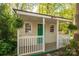 Close-up of cozy outbuilding with a green door and a welcoming porch, nestled among trees at 1220 Oakwood Ave, Gastonia, NC 28052