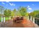 Outdoor dining area with a wooden table and chairs overlooking the backyard and a blue sky at 13713 Sunset Bluffs Cir, Huntersville, NC 28078