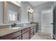 Bathroom with double sinks, stone counters, and wood cabinets at 13713 Sunset Bluffs Cir, Huntersville, NC 28078
