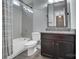 Bathroom with shower over tub, grey tile, dark wood vanity and granite countertop with mirror at 13713 Sunset Bluffs Cir, Huntersville, NC 28078