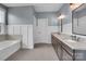 Bright bathroom with double sink vanity, granite countertop, wood cabinets, tub, and wainscotting at 13713 Sunset Bluffs Cir, Huntersville, NC 28078