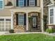 Close-up of the front entrance showcasing the stone facade, black door with oval window, and manicured landscaping at 1528 Ridge Haven Rd, Waxhaw, NC 28173