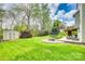 Manicured backyard featuring a stone patio with fire pit, trampoline, storage shed, and lush lawn at 1813 Robbins Meadows Dr, Waxhaw, NC 28173