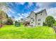 Expansive backyard featuring lush green lawn, mature trees, deck, and stone patio with a cozy fire pit at 1813 Robbins Meadows Dr, Waxhaw, NC 28173