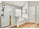 Bright bathroom featuring a tub, tiled shower with glass door, and neutral walls and cabinets at 1813 Robbins Meadows Dr, Waxhaw, NC 28173