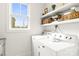 Modern laundry room featuring white appliances, open shelves, and a bright window at 211 Killian Rd, Stanley, NC 28164