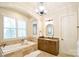 Relaxing primary bathroom features a soaking tub, wood cabinets, and natural stone tiling at 2415 Christenbury Hall Nw Dr, Concord, NC 28027