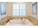 Bright bathroom featuring a soaking tub, stone surround, shuttered window, and modern fixtures at 2415 Christenbury Hall Nw Dr, Concord, NC 28027