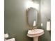 Stylish powder room featuring a pedestal sink, gold mirror, and elegant fixtures at 2415 Christenbury Hall Nw Dr, Concord, NC 28027