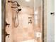 Stone shower featuring bronze fixtures, a glass enclosure, and a convenient built-in shelf at 2415 Christenbury Hall Nw Dr, Concord, NC 28027