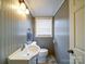 Cozy half bathroom with a white sink, toilet, and decorative mirror, enhanced by stylish gray paint at 24436 Nc 24/27 Hwy, Albemarle, NC 28001