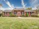 Inviting brick house featuring a symmetrical facade, red door, and manicured landscaping, enhanced by a stone walkway at 24436 Nc 24/27 Hwy, Albemarle, NC 28001