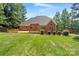 View of the brick home with a spacious lawn, wooden deck, and landscaped garden at 255 Honeysuckle Creek Loop, Mooresville, NC 28117