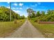 Long private driveway with stately brick pillars at entrance, on a bright day with blue skies and wispy clouds at 2710 Wyatt Grove Church Rd, Richfield, NC 28137