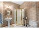 Cozy bathroom features a pedestal sink, framed mirror, glass-enclosed shower, and decorative wallpaper at 307 Stillwater Rd, Troutman, NC 28166