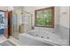 Clean bathroom featuring a jetted tub, glass shower, and a window providing natural light at 307 Stillwater Rd, Troutman, NC 28166