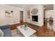 Cozy living room with a brick fireplace, hardwood floors, and access to other living spaces for seamless living at 3911 Kitley Pl, Charlotte, NC 28210
