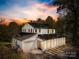 Charming two-story home with a white exterior, black shutters, and well-manicured landscaping at sunset at 4375 Creek Ave, Midland, NC 28107