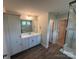 Bathroom with double vanity, shower with glass door, white cabinets and wood look floor at 5100 Verona Rd # 96, Charlotte, NC 28213