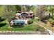 An aerial view of a beautiful stone home with a sparkling pool and a lush green lawn at 7424 Windy Pine Cir, Denver, NC 28037