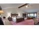 Spacious primary bedroom with exposed beams and a sitting area by the window overlooking the backyard at 7424 Windy Pine Cir, Denver, NC 28037